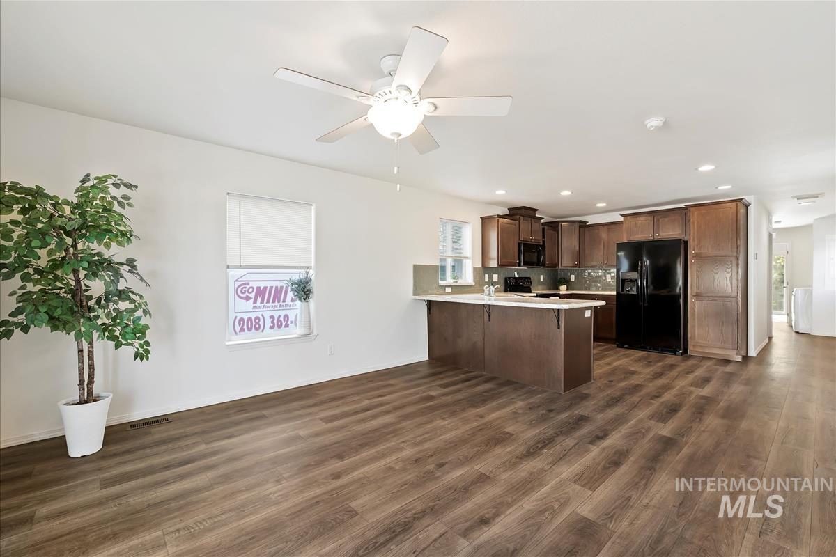 Kitchen featuring open floor plan, black appliances, dark wood finished floors, a peninsula, and recessed lighting