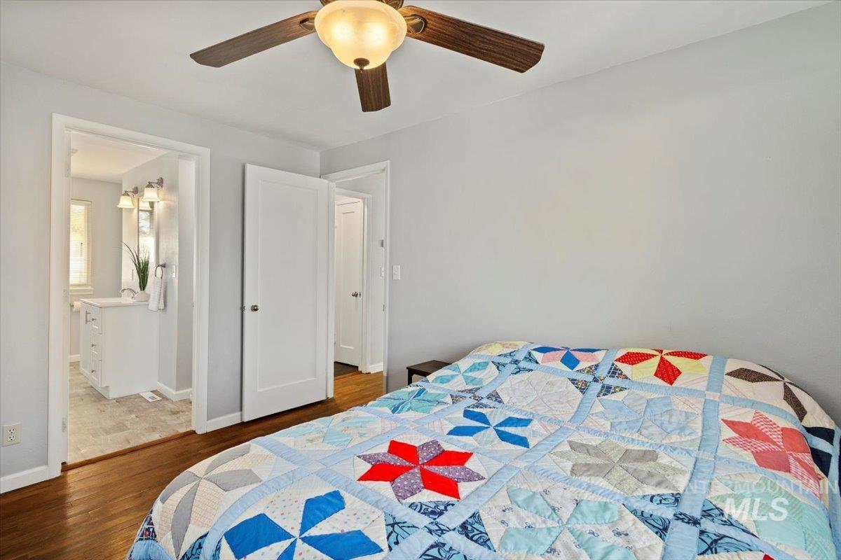 Bedroom with wood finished floors, a ceiling fan, and connected bathroom