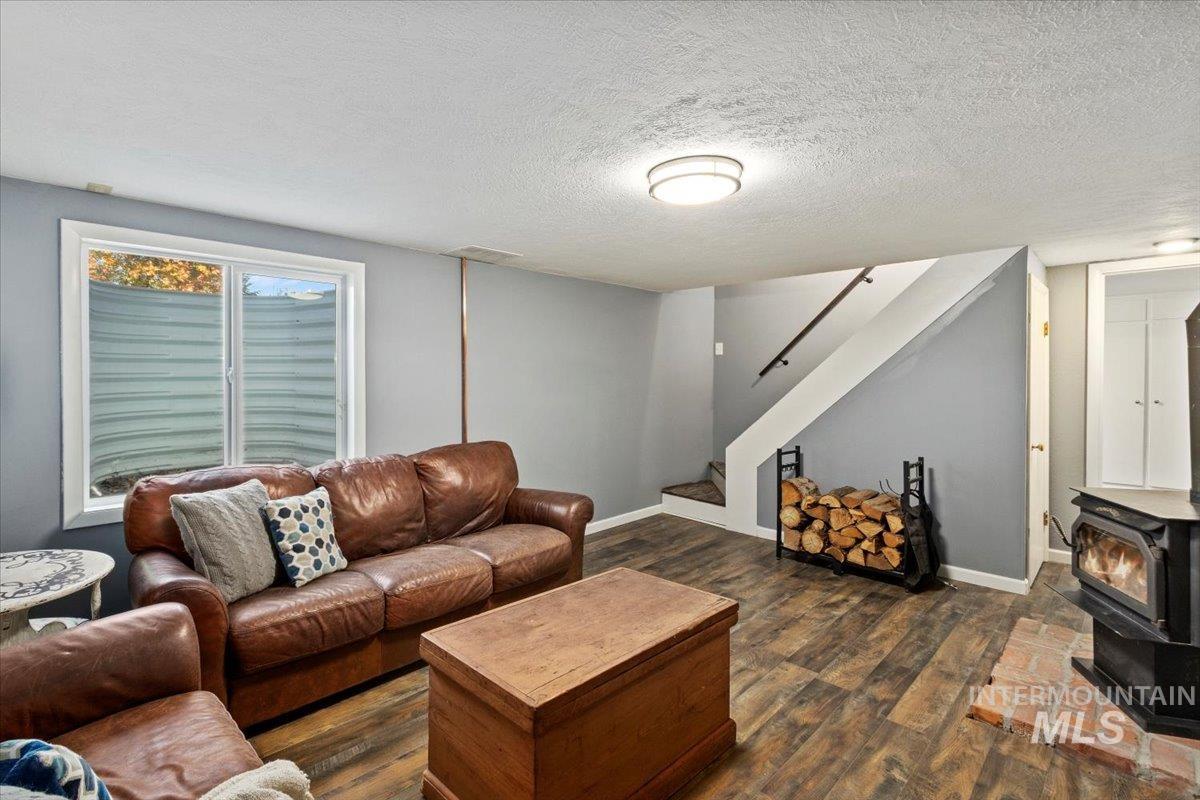 Living area with dark wood-style floors, a textured ceiling, a wood stove, and stairway