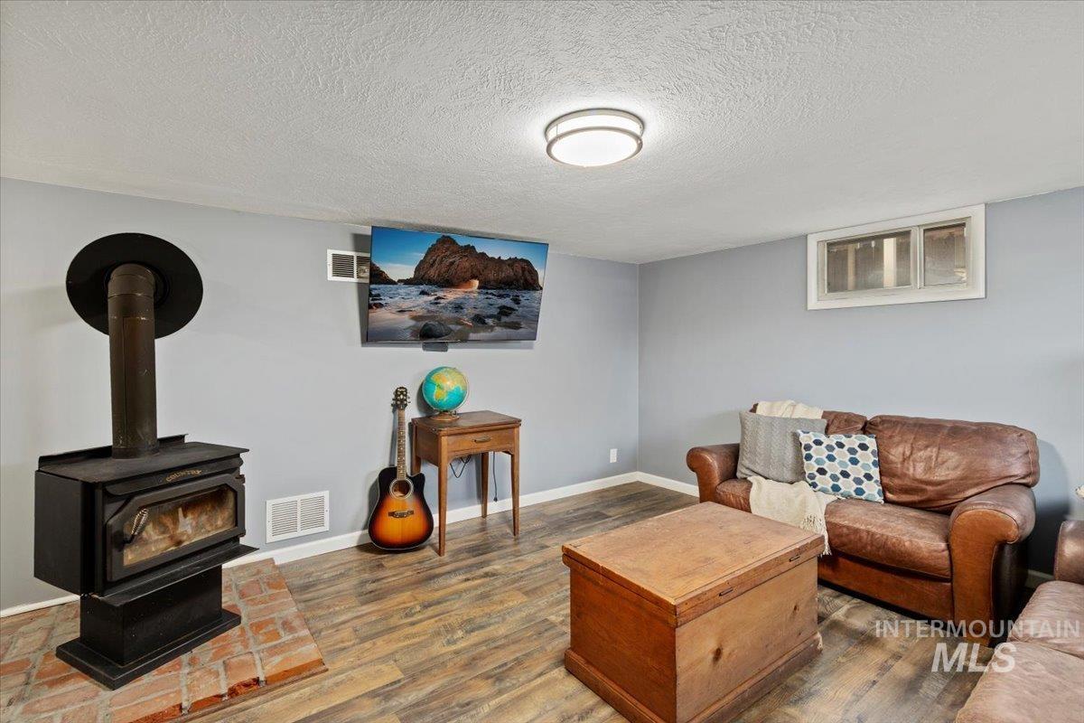 Living area featuring a wood stove, wood finished floors, and a textured ceiling