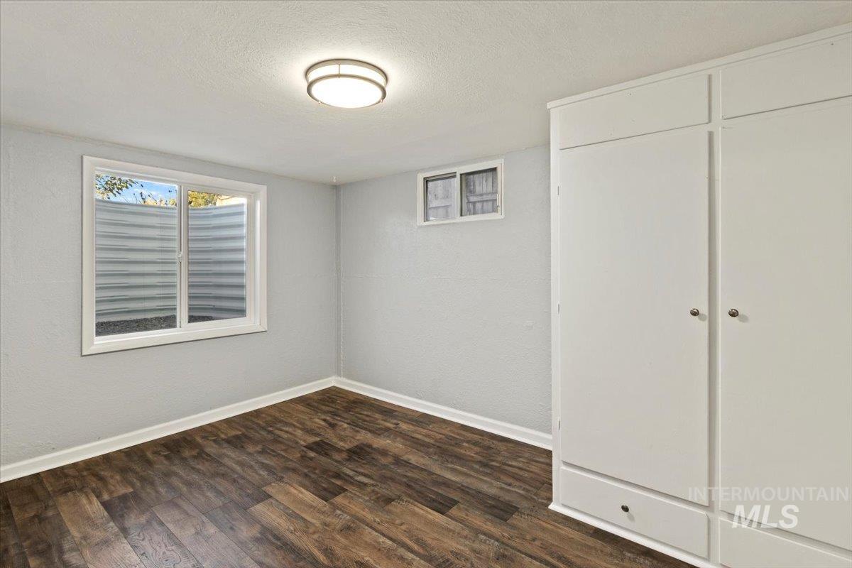 Unfurnished bedroom featuring a textured ceiling, dark wood finished floors, a closet, and a textured wall