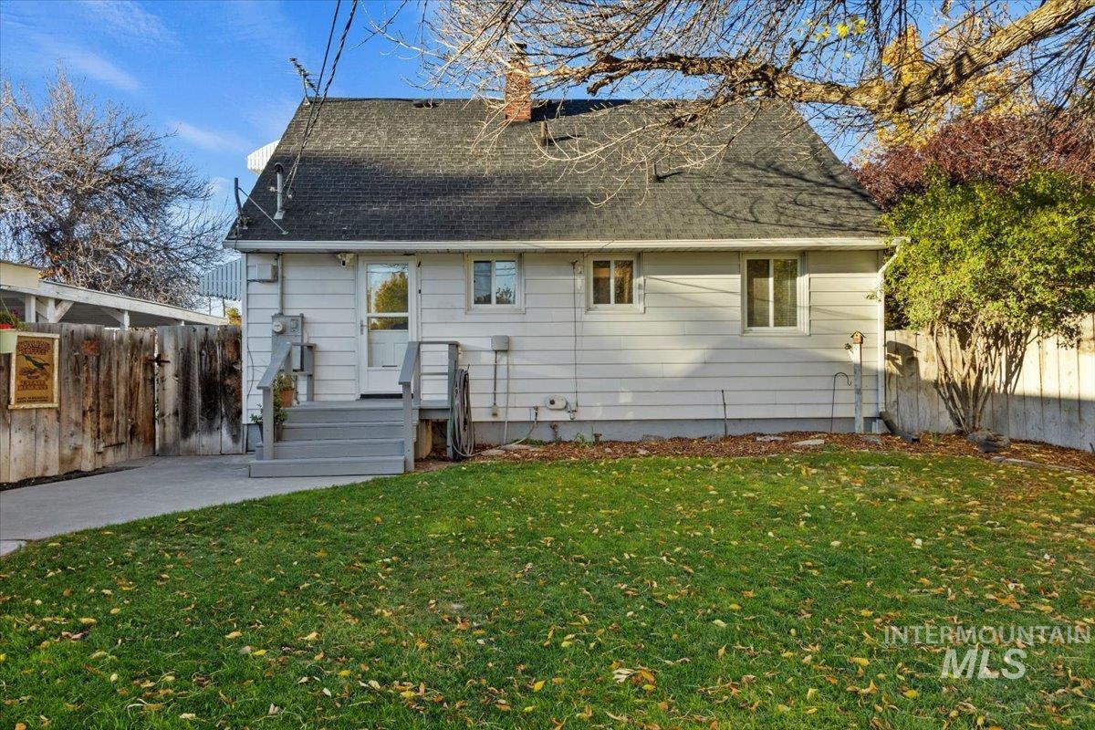 Rear view of property featuring a shingled roof, a chimney, and a patio