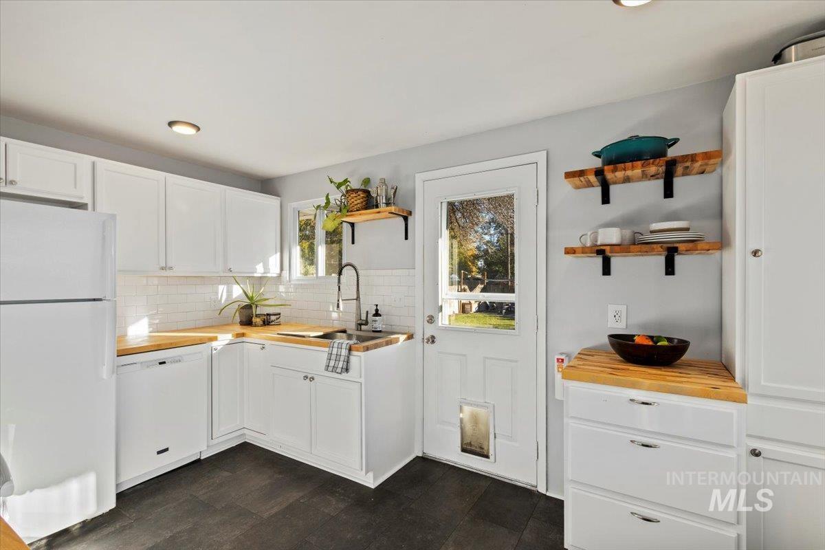 Kitchen with white cabinets, white appliances, wood counters, and recessed lighting