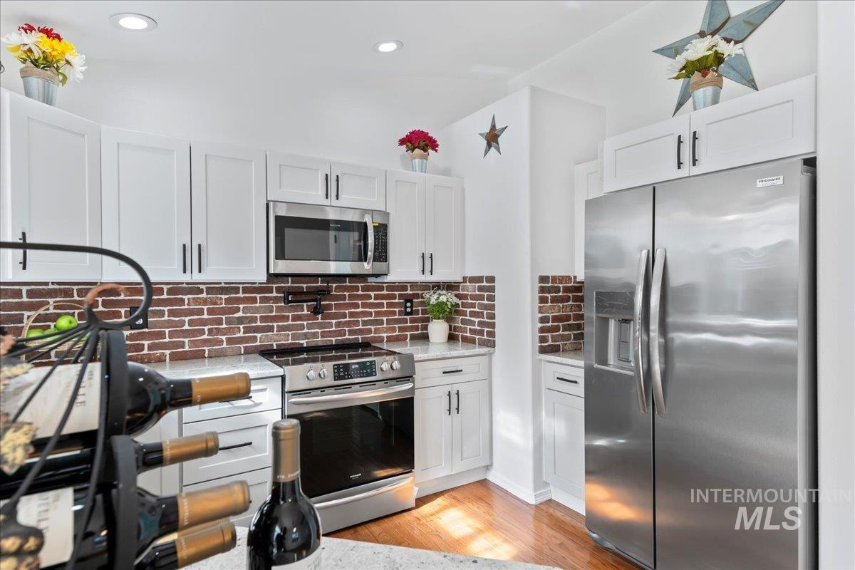 Kitchen featuring appliances with stainless steel finishes, light wood finished floors, white cabinets, and recessed lighting