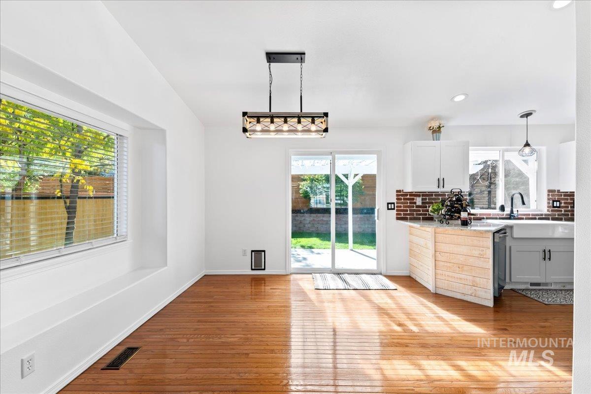 Kitchen featuring backsplash, healthy amount of natural light, light wood-type flooring, white cabinets, and recessed lighting