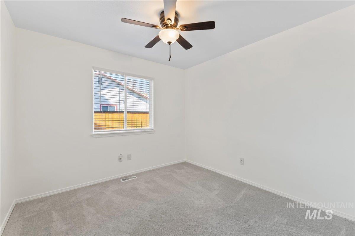 Carpeted spare room featuring baseboards and a ceiling fan