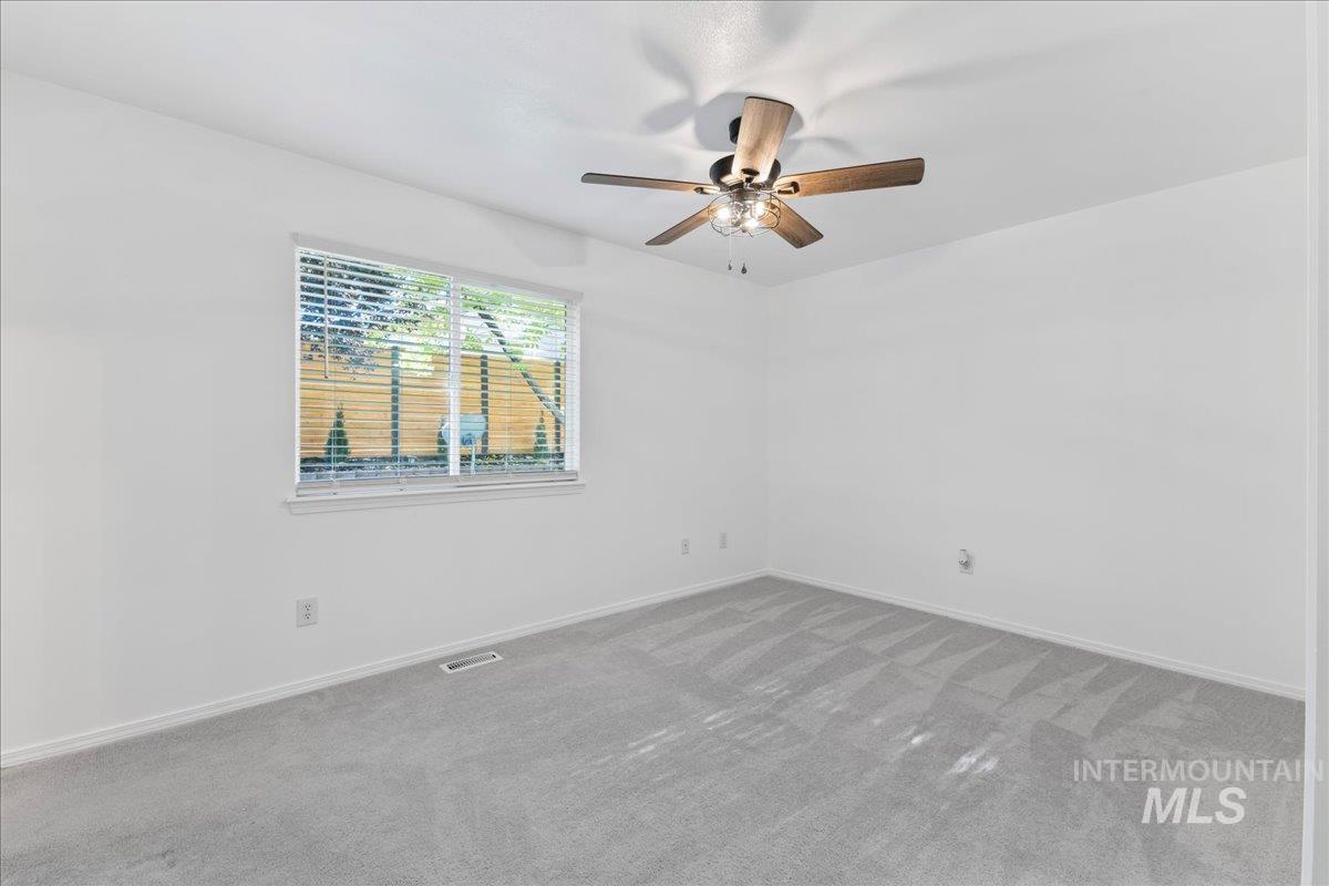 Carpeted spare room featuring baseboards and ceiling fan