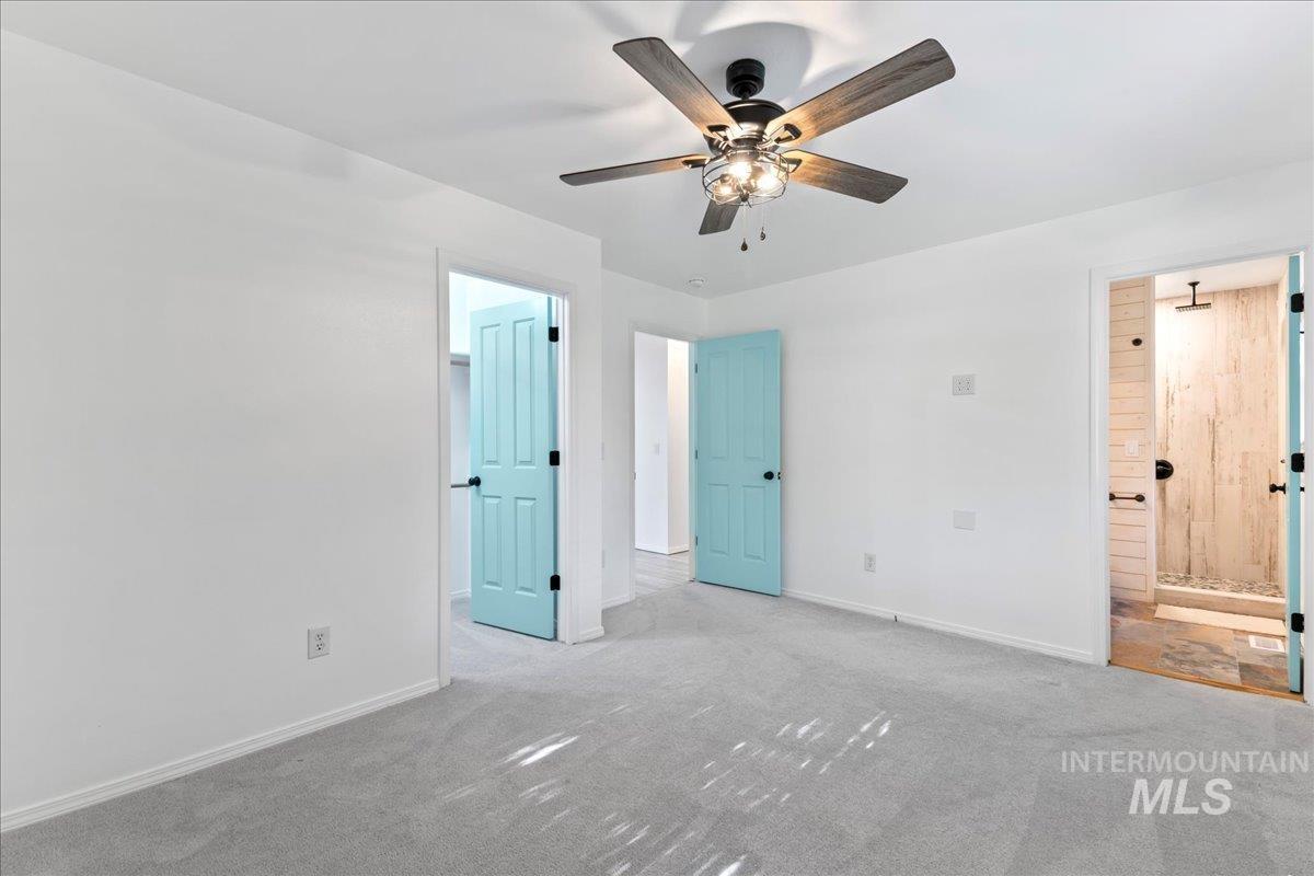 Unfurnished bedroom with connected bathroom, carpet, ceiling fan, and a spacious closet