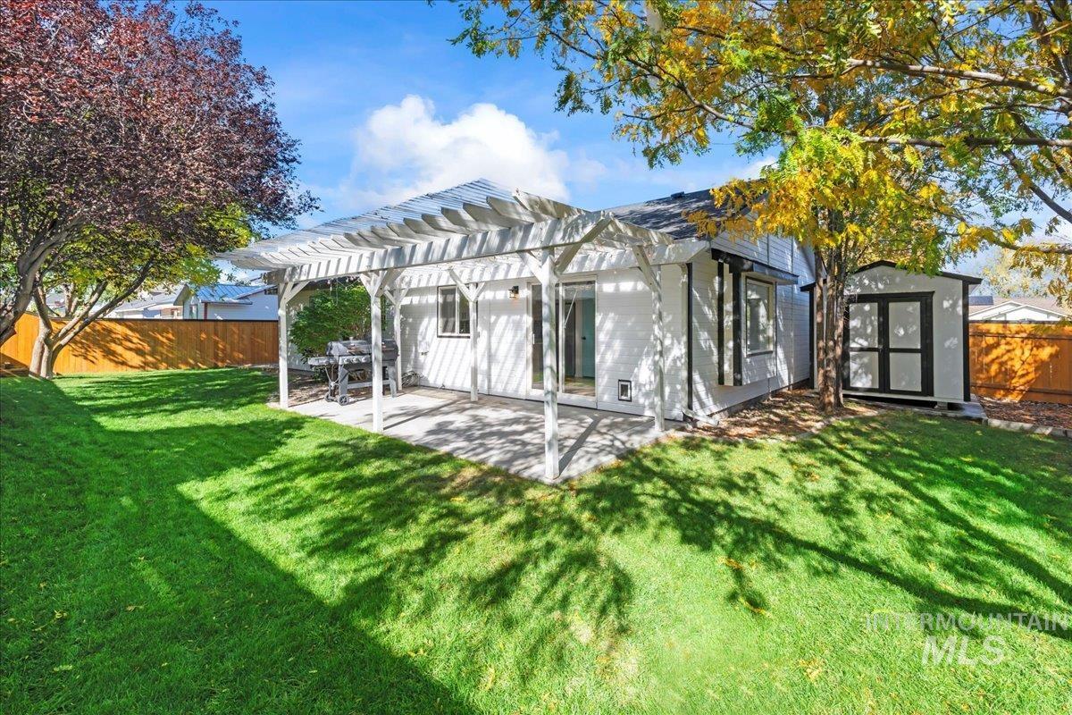 Back of house featuring a pergola, a fenced backyard, a storage shed, and a patio