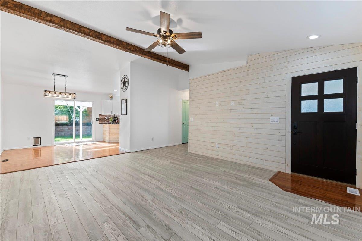 Unfurnished living room with wooden walls, wood finished floors, and ceiling fan