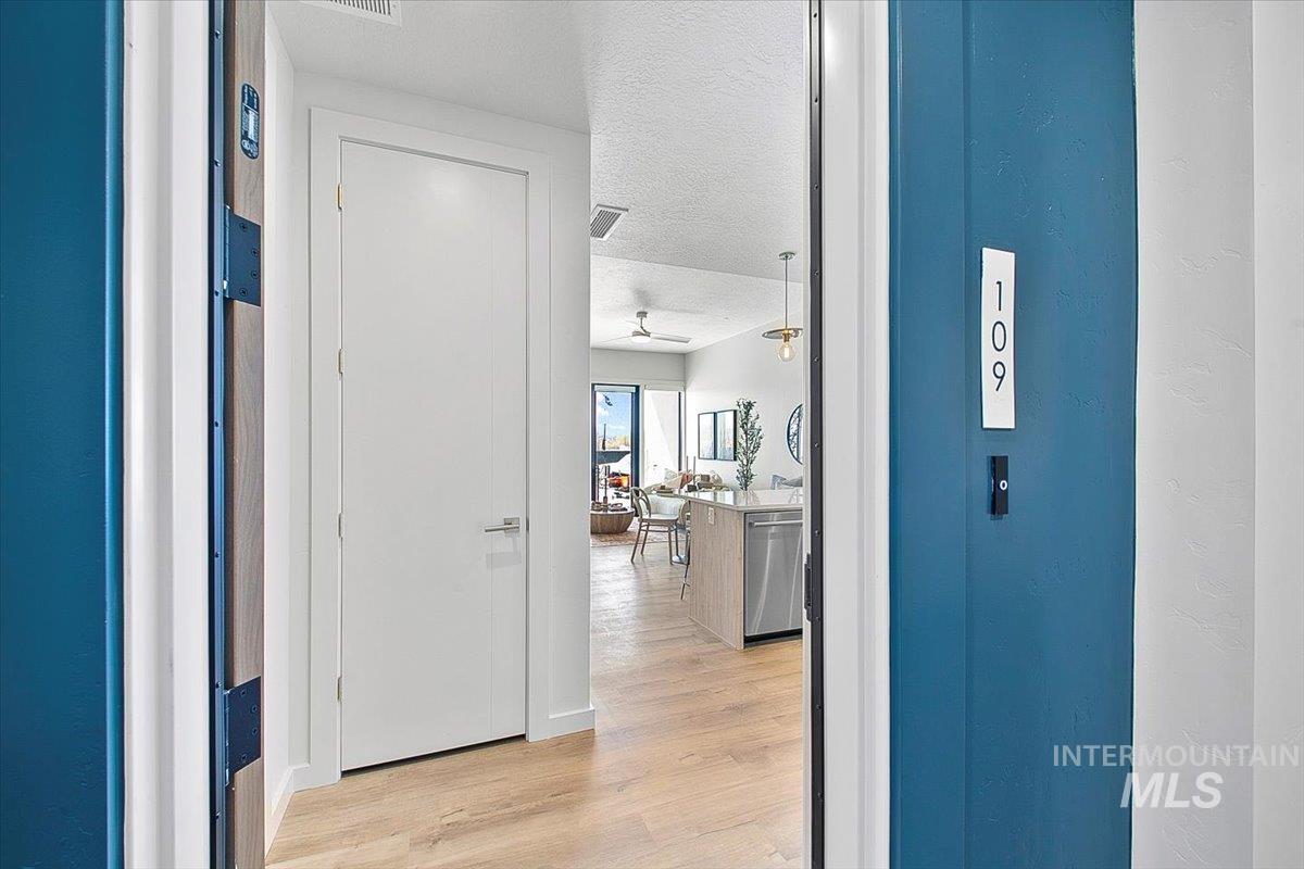 Corridor with a textured ceiling and light wood finished floors