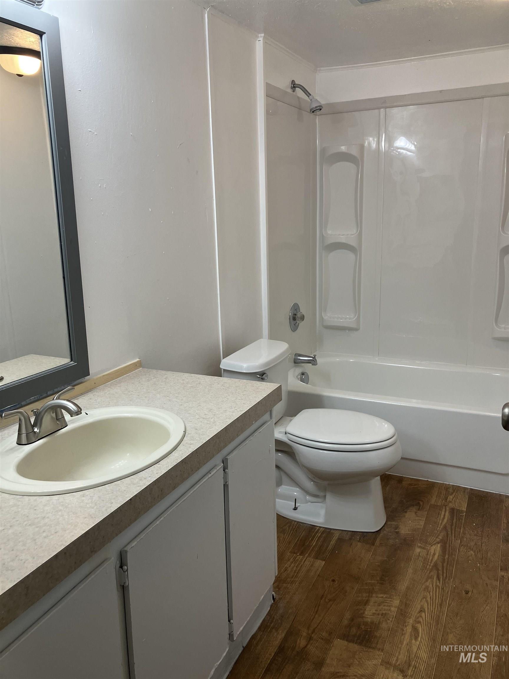 Bathroom featuring dark wood finished floors, vanity, and shower / washtub combination