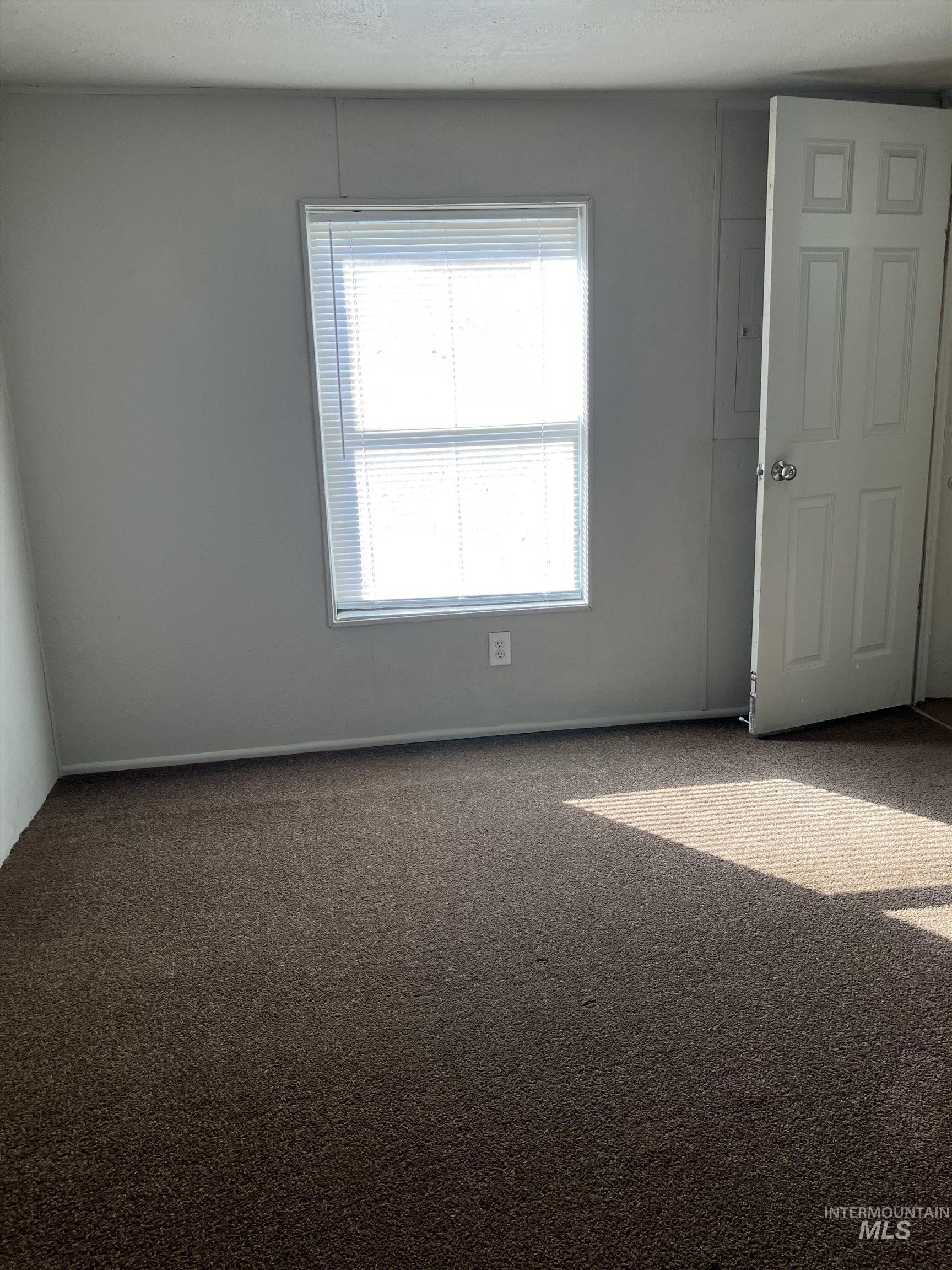 Carpeted spare room featuring baseboards