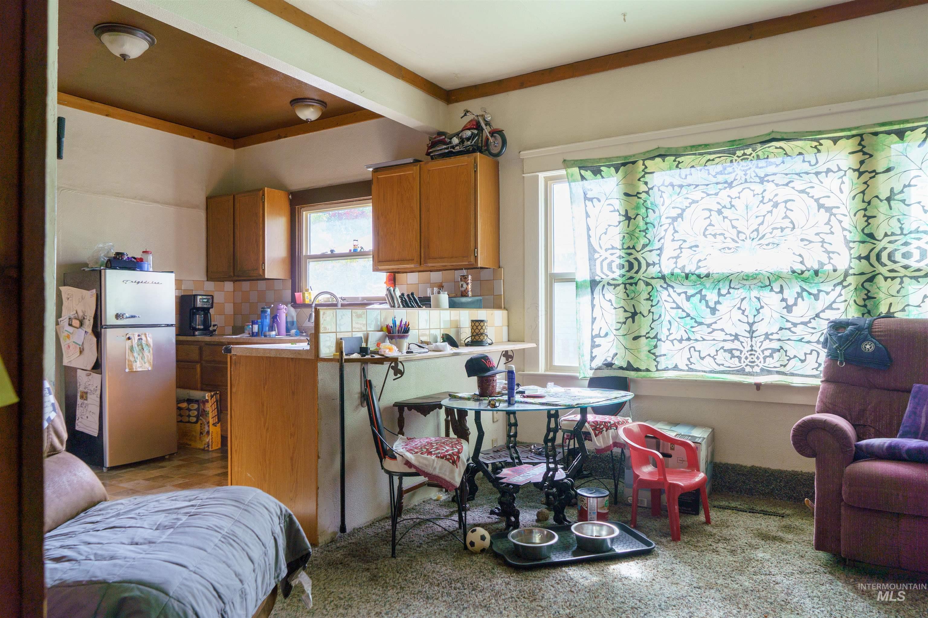 Kitchen featuring brown cabinets, freestanding refrigerator, tasteful backsplash, beam ceiling, and a peninsula