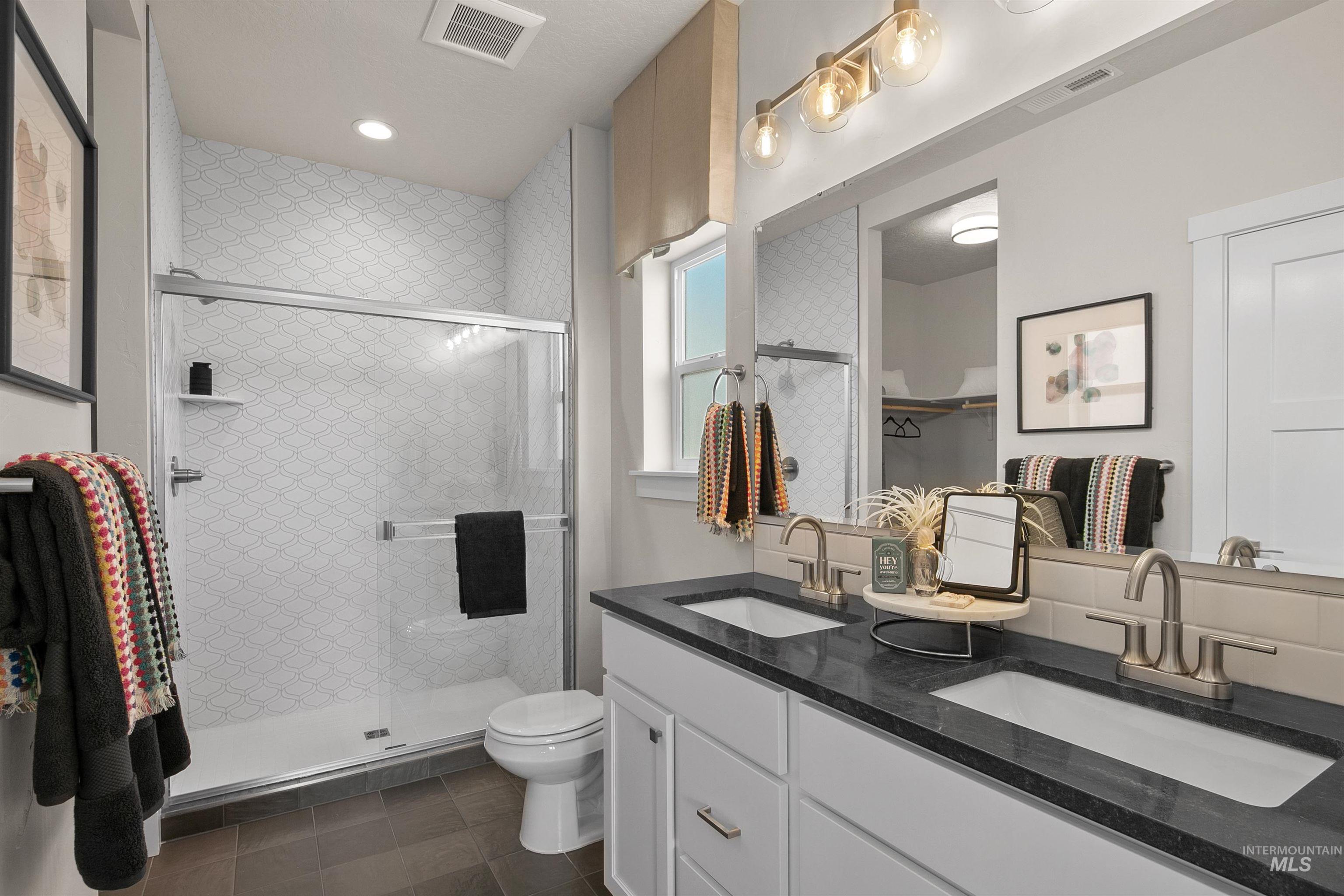 Bathroom with double vanity, a stall shower, dark tile patterned floors, recessed lighting, and a spacious closet
