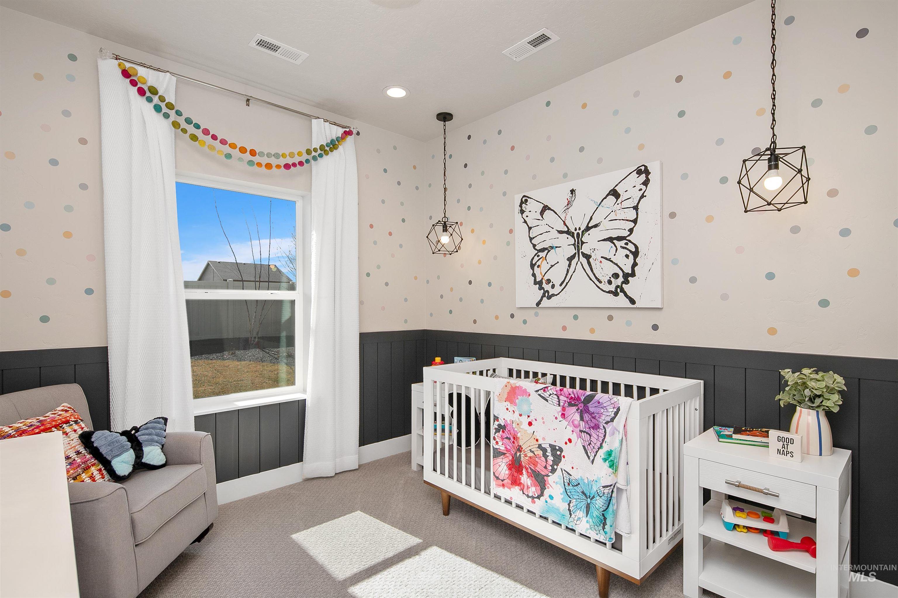 Bedroom with a nursery area, carpet floors, wallpapered walls, and a wainscoted wall