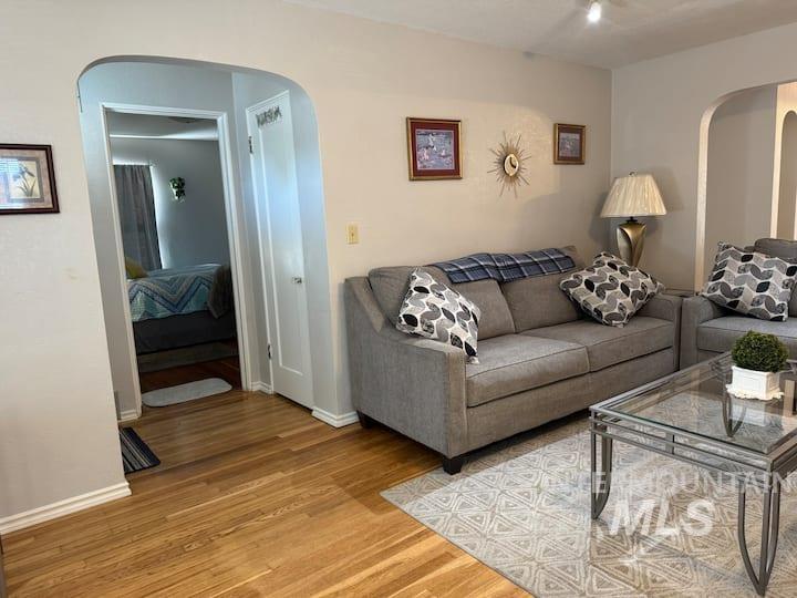 Living room with arched walkways and wood finished floors