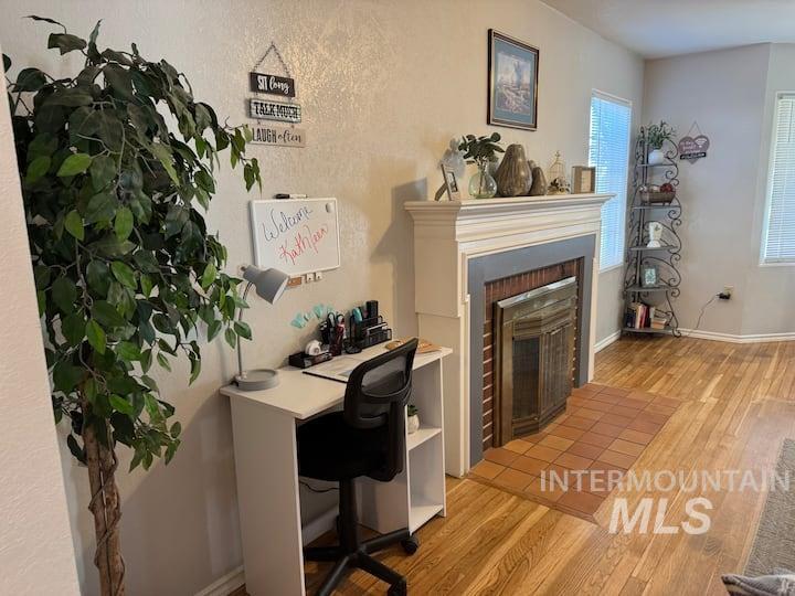 Office area featuring light wood-style floors and a fireplace