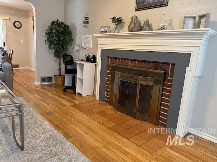 Living area with arched walkways, light wood-type flooring, and a fireplace