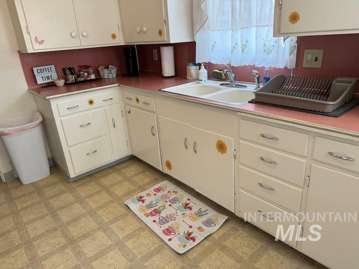 Kitchen featuring light floors, white cabinets, and light countertops