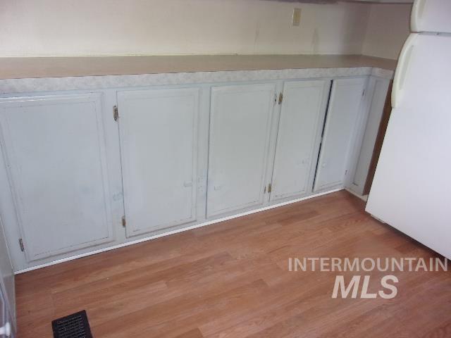 Detailed view of freestanding refrigerator and wood finished floors