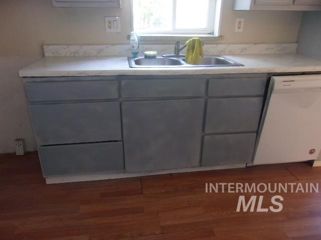 Kitchen with light countertops, white dishwasher, dark wood finished floors, and gray cabinetry