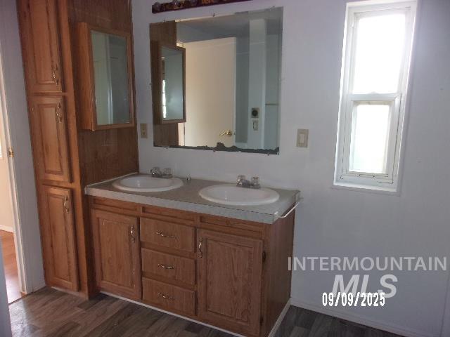 Full bath with double vanity and dark wood-style floors