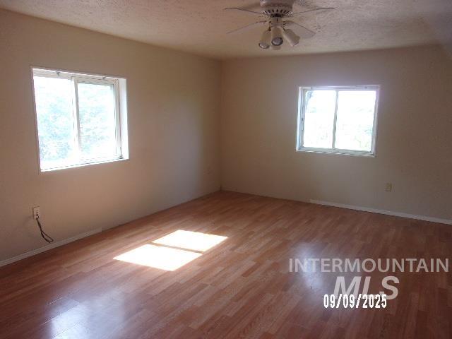 Spare room with a textured ceiling, wood finished floors, and ceiling fan