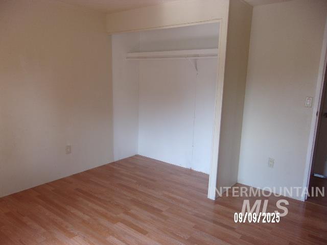 Unfurnished bedroom with wood finished floors and a closet