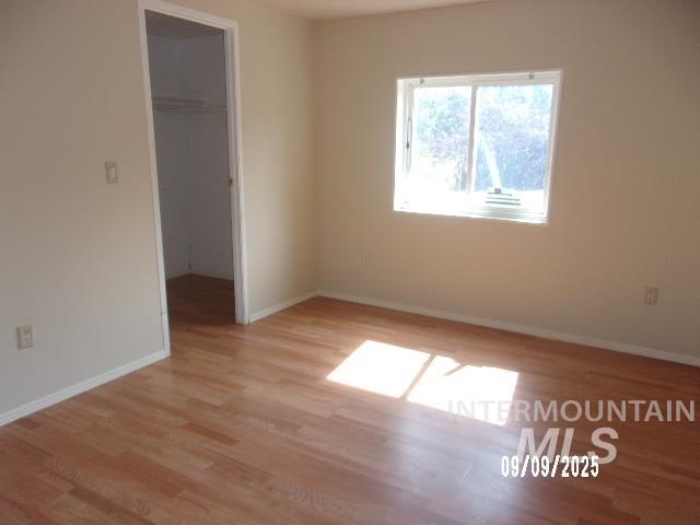 Unfurnished bedroom featuring light wood finished floors and a spacious closet