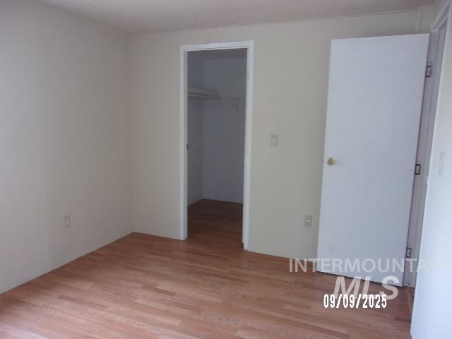 Unfurnished bedroom with light wood-style flooring and a walk in closet