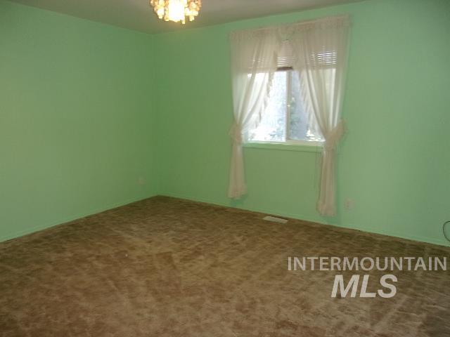 Carpeted spare room featuring a chandelier