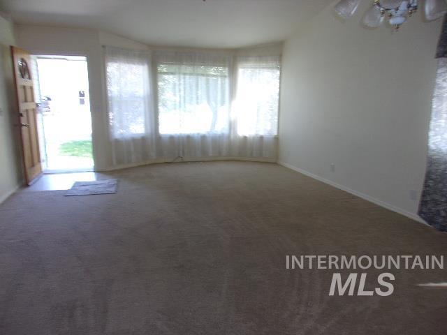 Unfurnished living room featuring carpet and baseboards