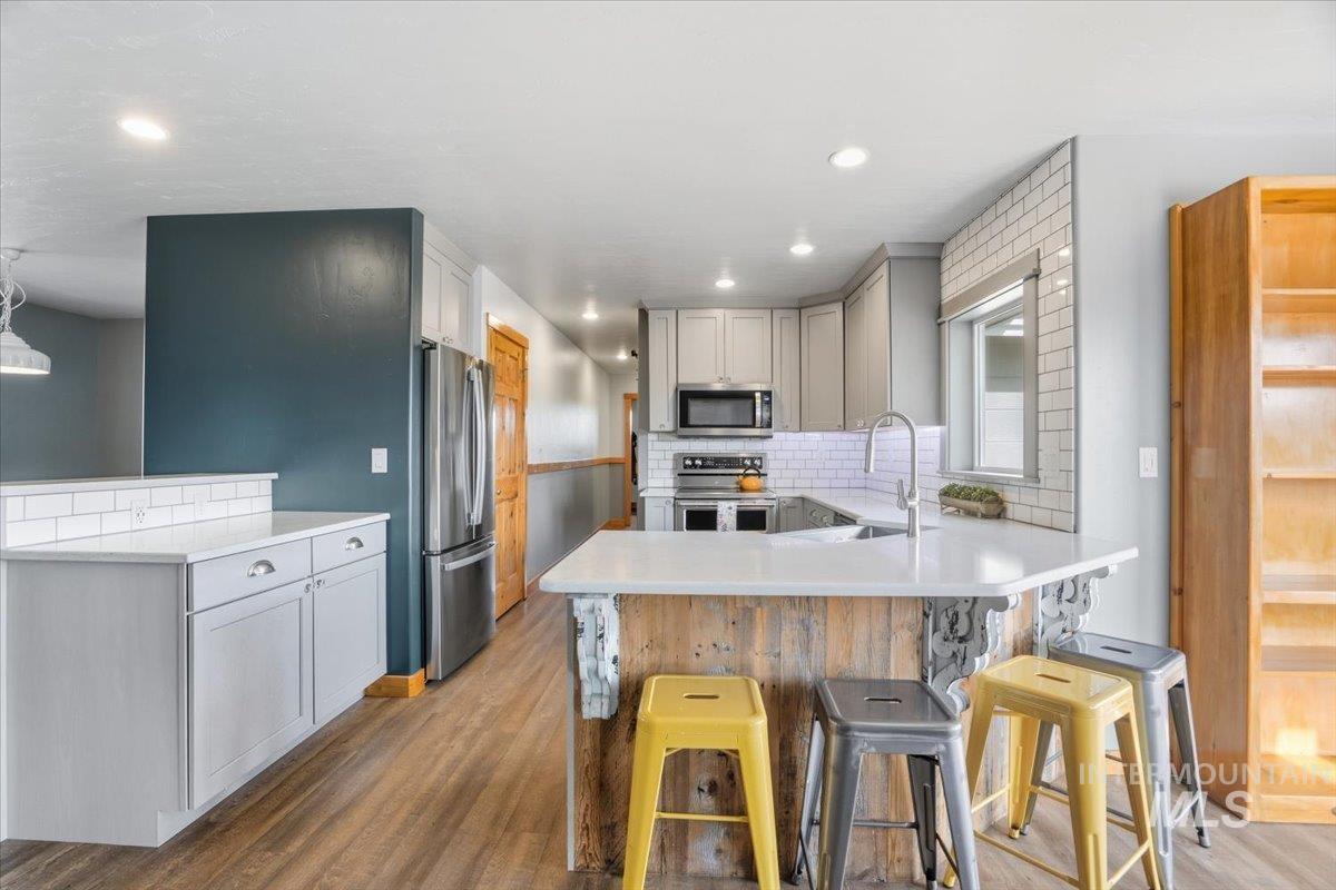 Kitchen featuring a peninsula, tasteful backsplash, appliances with stainless steel finishes, light wood-type flooring, and recessed lighting
