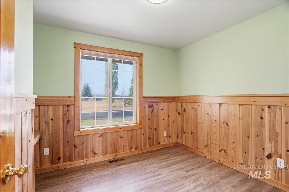 Unfurnished room with wood finished floors, wooden walls, and a wainscoted wall