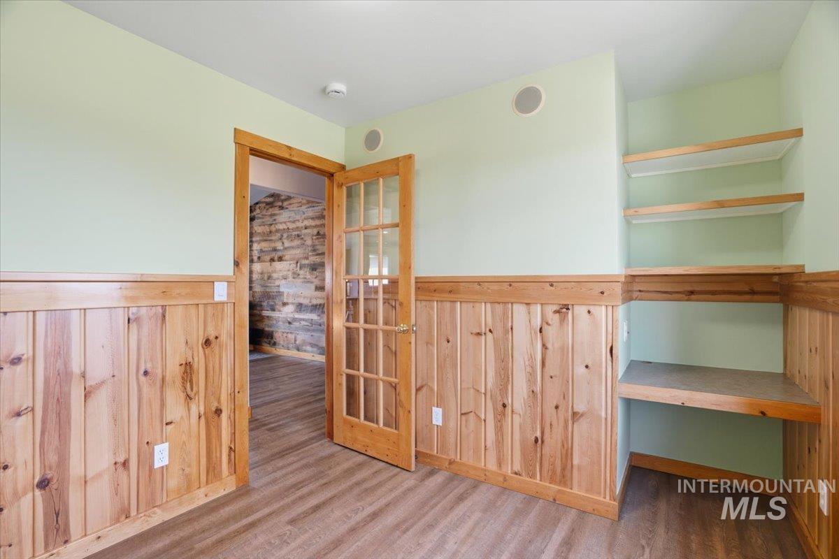Unfurnished room featuring wood walls, wood finished floors, and wainscoting