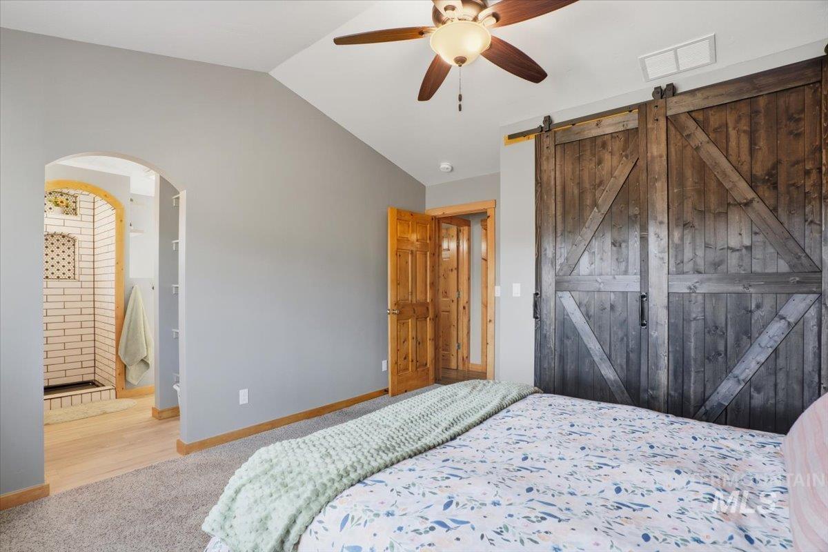 Bedroom featuring connected bathroom, carpet floors, ceiling fan, lofted ceiling, and wood finished floors