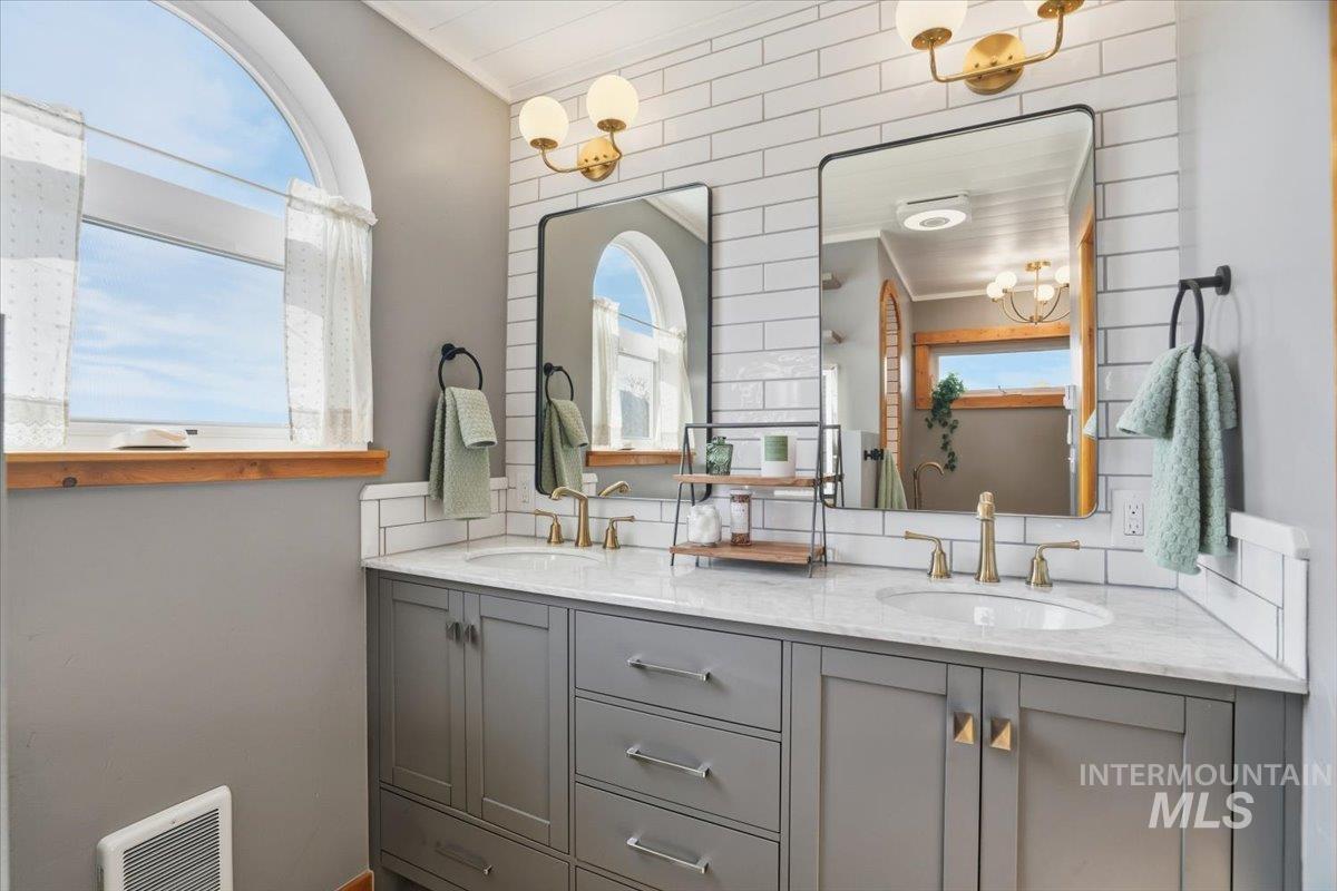 Bathroom featuring plenty of natural light, double vanity, and a chandelier