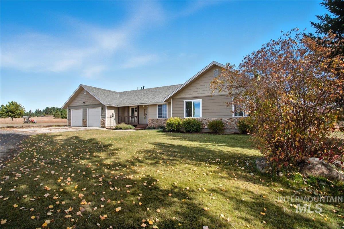 Single story home featuring a porch, stone siding, driveway, a front yard, and an attached garage