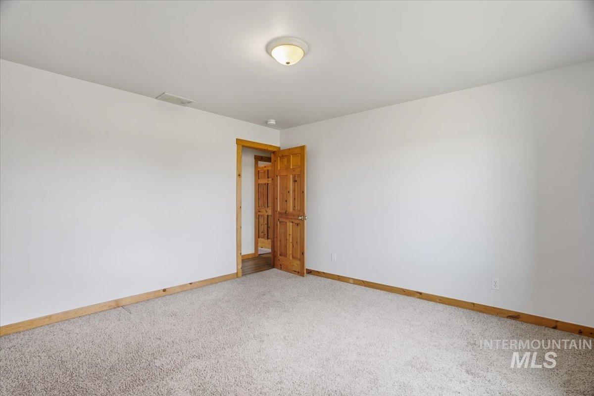 Empty room featuring baseboards and light carpet