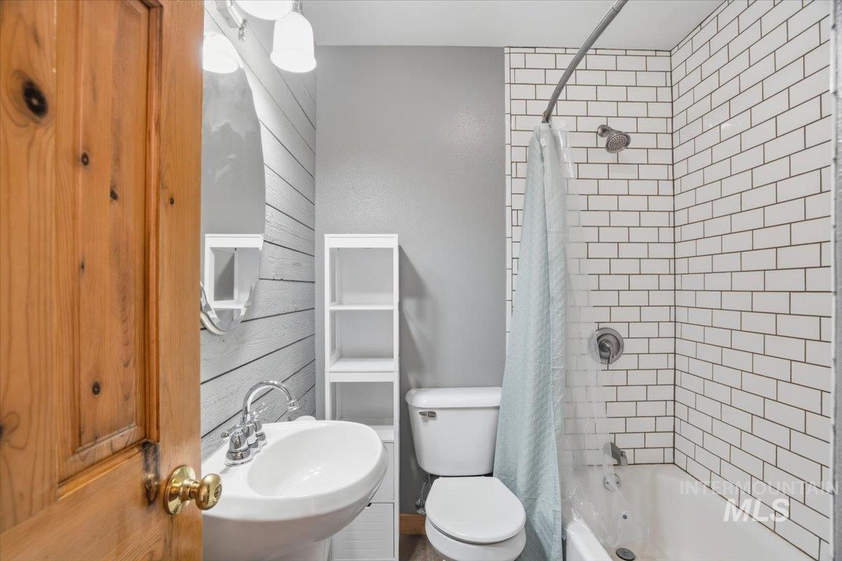Bathroom featuring shower / bath combination with curtain and toilet