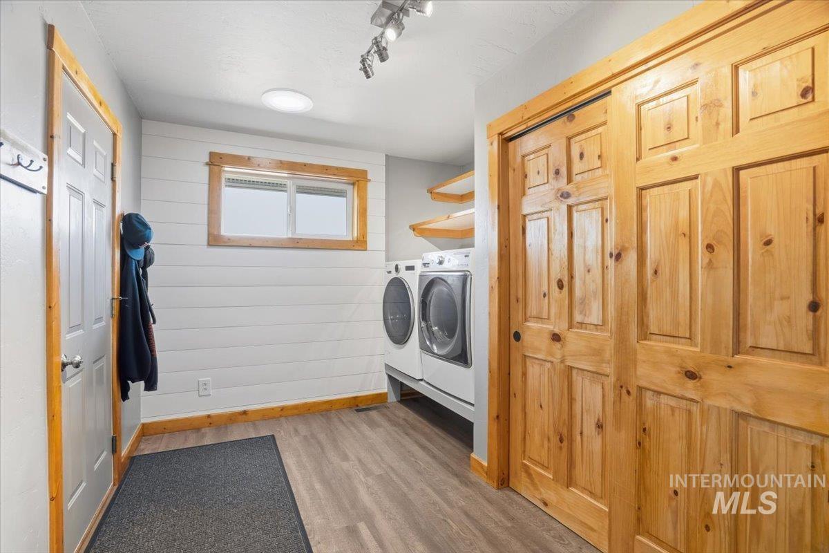 Laundry room featuring light wood finished floors, washing machine and clothes dryer, and rail lighting