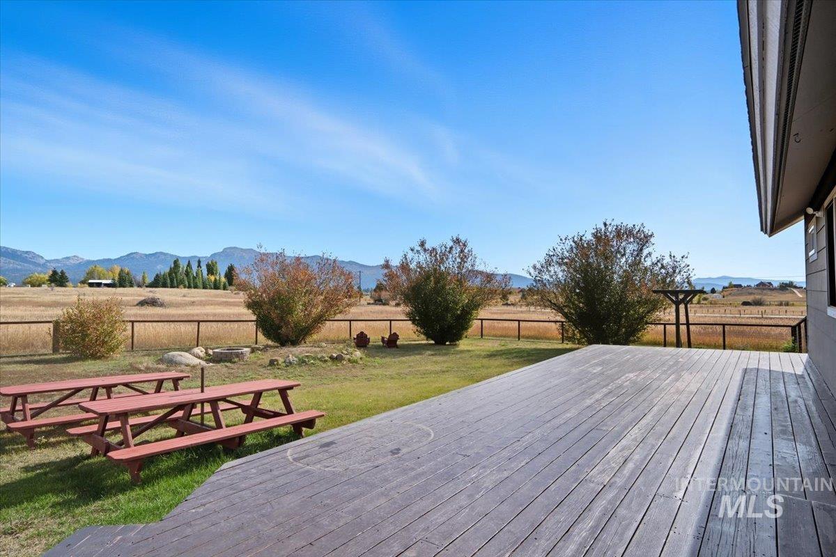 Wooden terrace featuring a fenced backyard, a rural view, and a mountain view