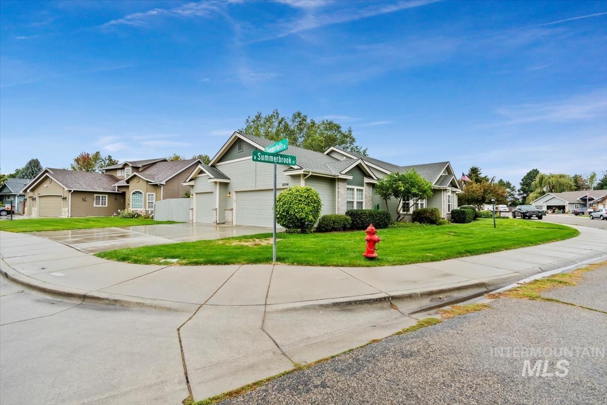 View of front of property featuring a residential view, concrete driveway, a front yard, and an attached garage