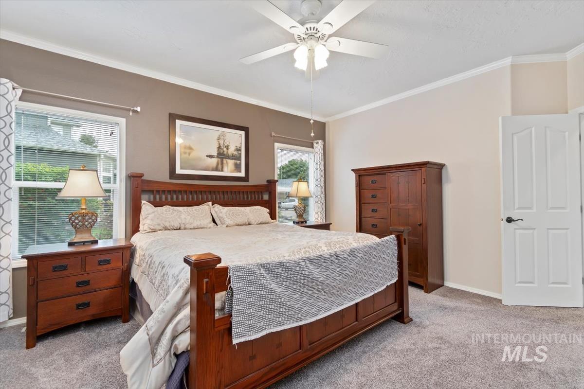 Bedroom featuring light carpet, ornamental molding, and ceiling fan