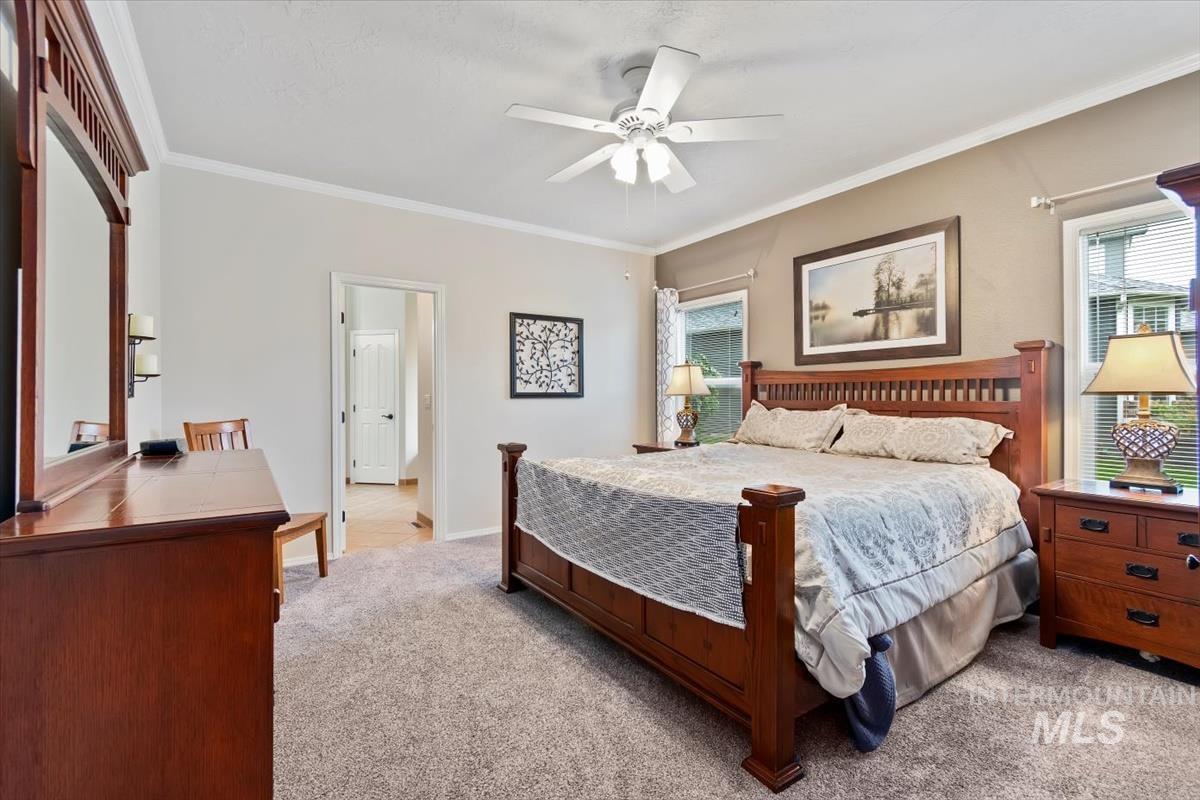 Bedroom featuring crown molding, light carpet, and a ceiling fan