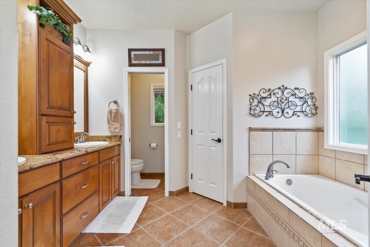 Bathroom featuring vanity, light tile patterned flooring, and a bath