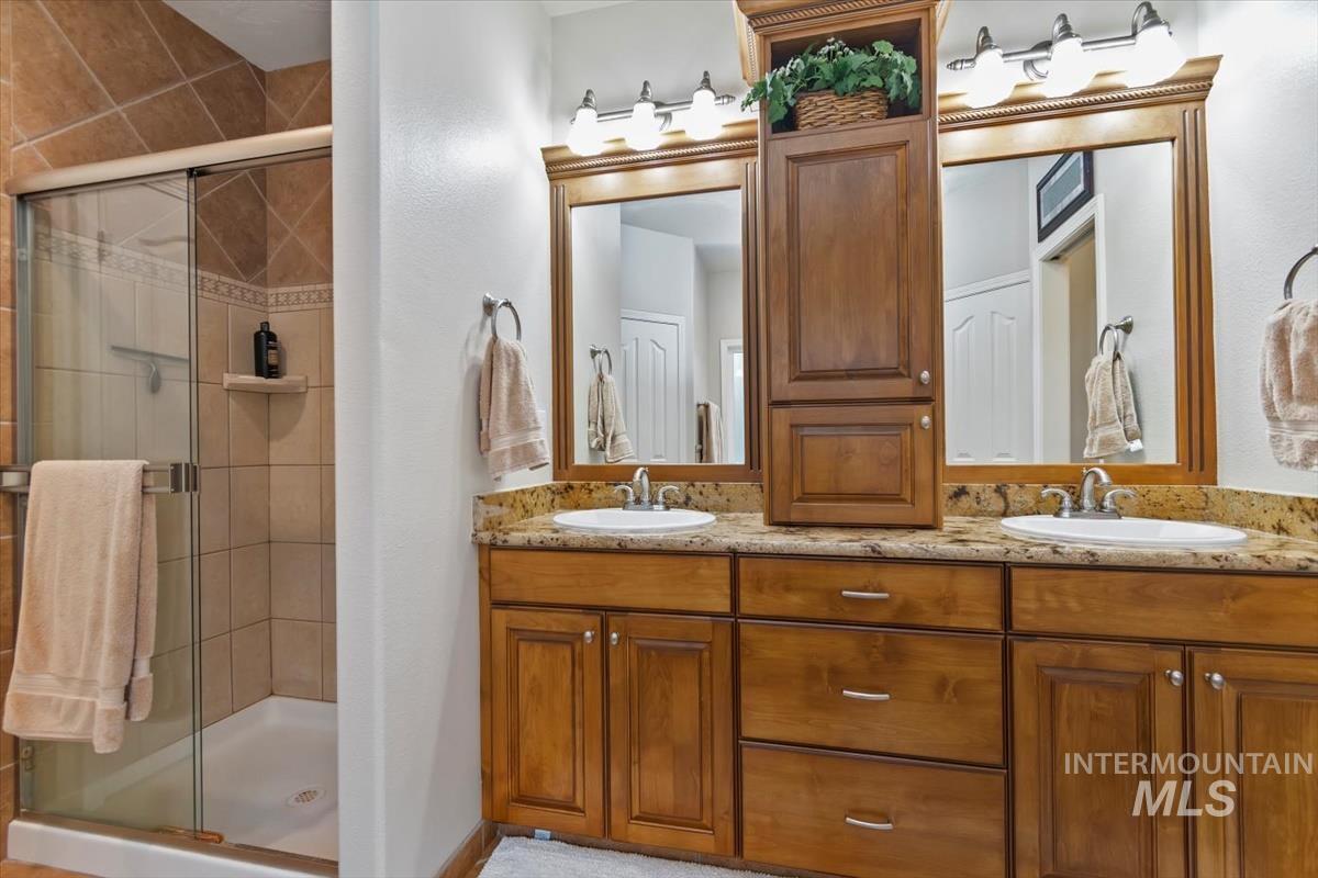 Bathroom featuring double vanity and a shower stall