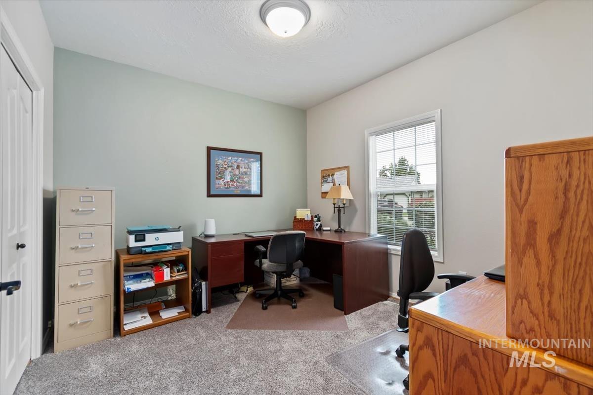 Office with light colored carpet and a textured ceiling