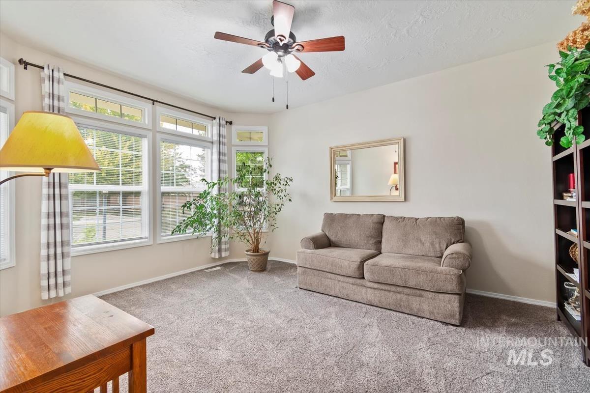 Carpeted living area featuring a ceiling fan and a textured ceiling